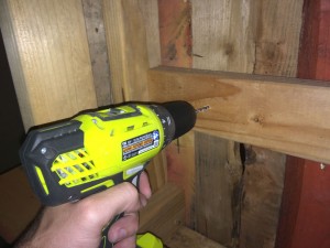 Drill through the existing holes from the backside of the bar to put a guide hole through the wood facade