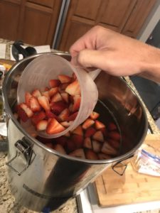 Adding fresh strawberries to kombucha for natural fruit flavoring